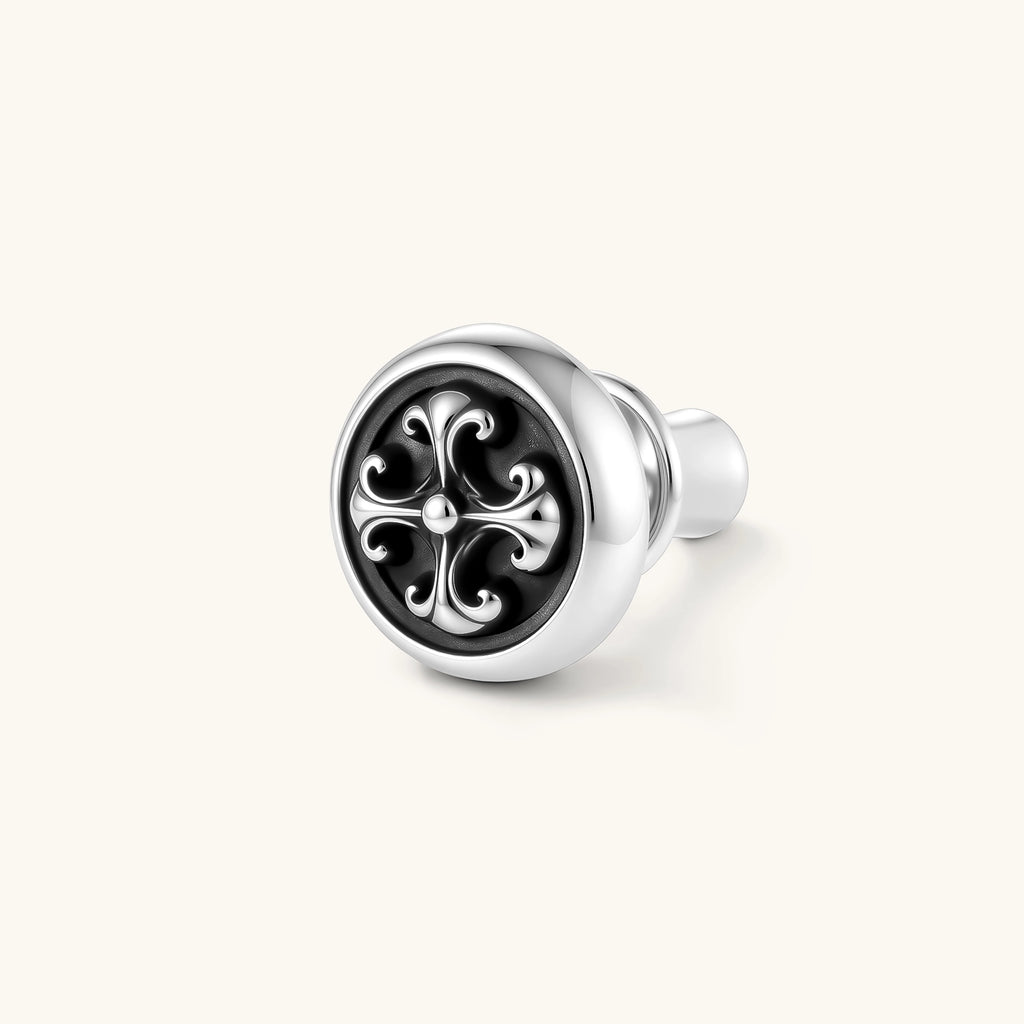 Round sterling silver stud earring with black enamel background and fleur-de-lis cross motif, butterfly push-back closure.