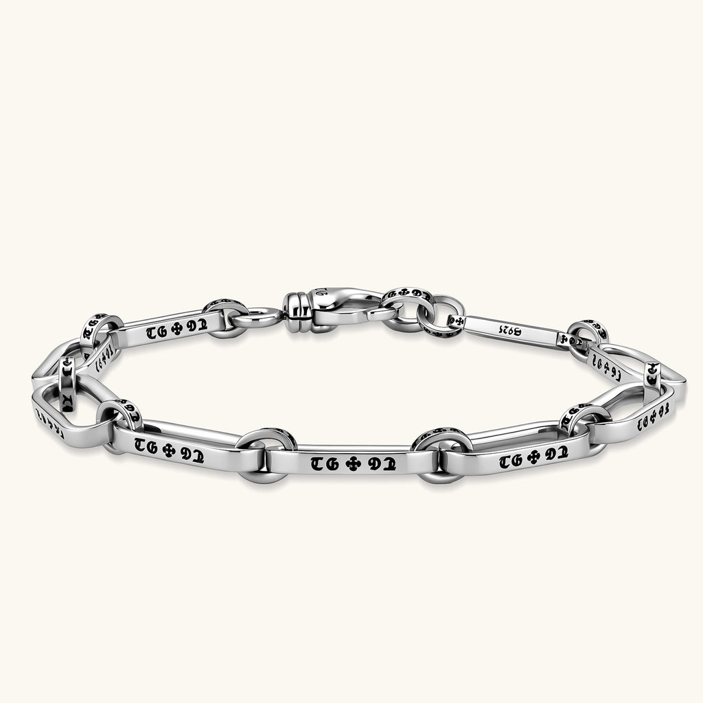 Sterling silver bar-link chain bracelet with oxidized Gothic text engravings and toggle clasp, 7.3mm wide, on white background.