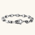 Sterling silver bracelet with linked skull motifs, decorative scroll engravings, and a large skull lobster-claw clasp.