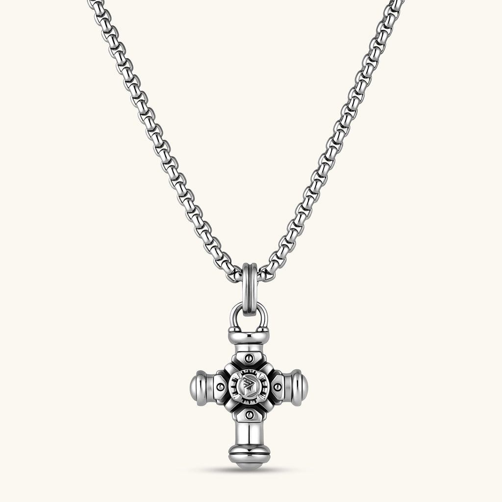 Sterling silver cross pendant with cylindrical arms, floral center medallion, and engraved emblem, shown solo and on a box chain.