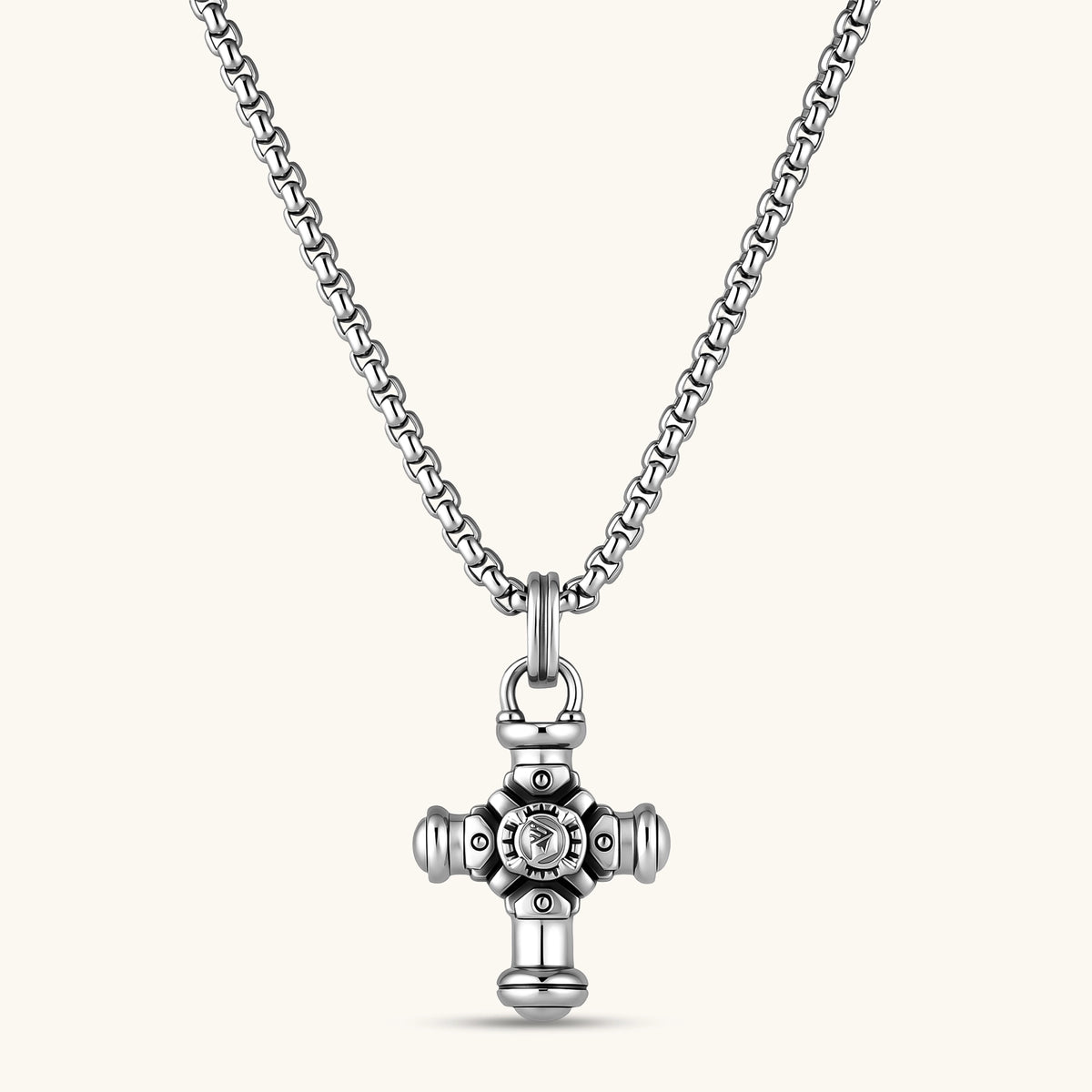 Sterling silver cross pendant with cylindrical arms, floral center medallion, and engraved emblem, shown solo and on a box chain.