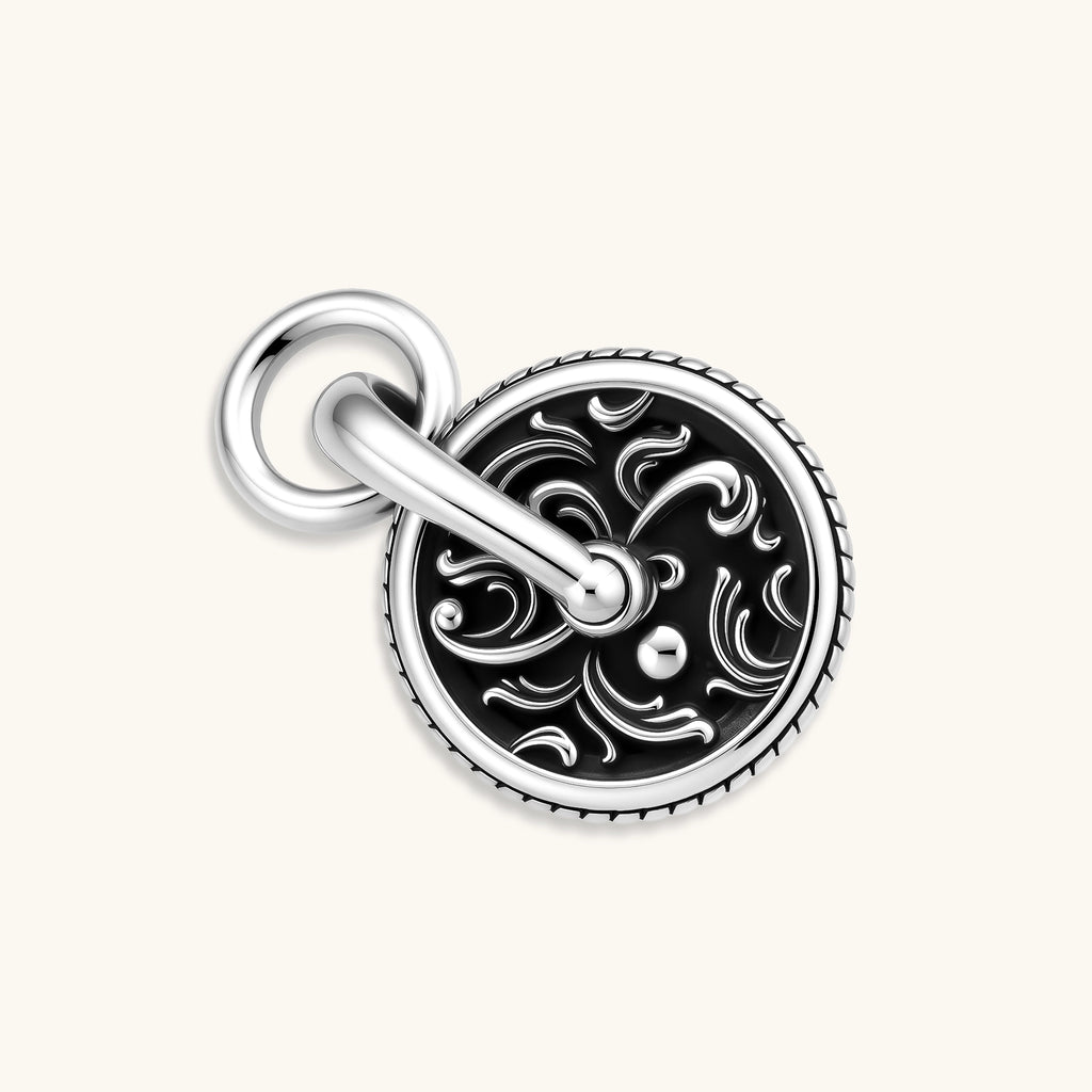 Round 925 sterling silver medallion charm with black enamel fill, scrollwork engraving, rope border, and bold bail ring.