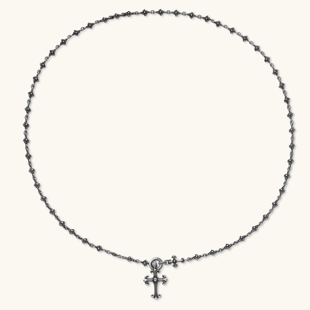 Sterling silver necklace with ornate floral-link chain, ring clasp, cross toggle bar, and Gothic fleur cross pendant.